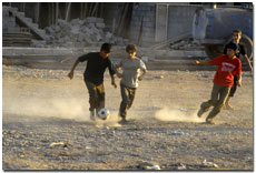Three boys playing football dusty